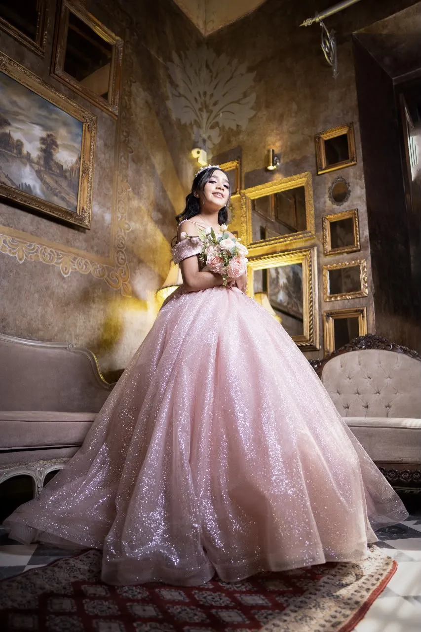 Quinceañera con vestido rosa de glitter y ramo en salón vintage